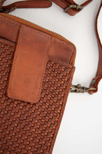 Close-up of woven leather texture and magnetic clasp on brown wallet