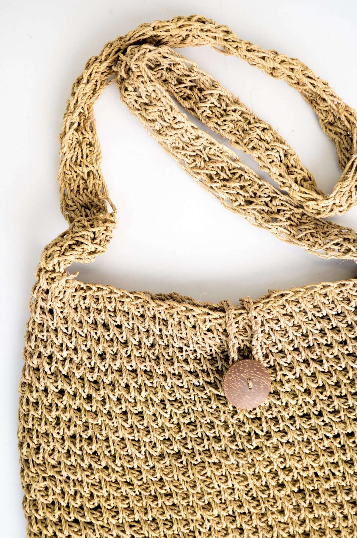 Close-up detail of rattan purse showing woven strap and button closure