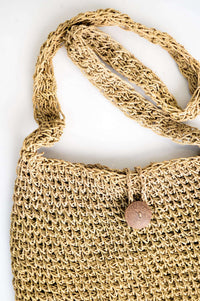 Close-up detail of rattan purse showing woven strap and button closure