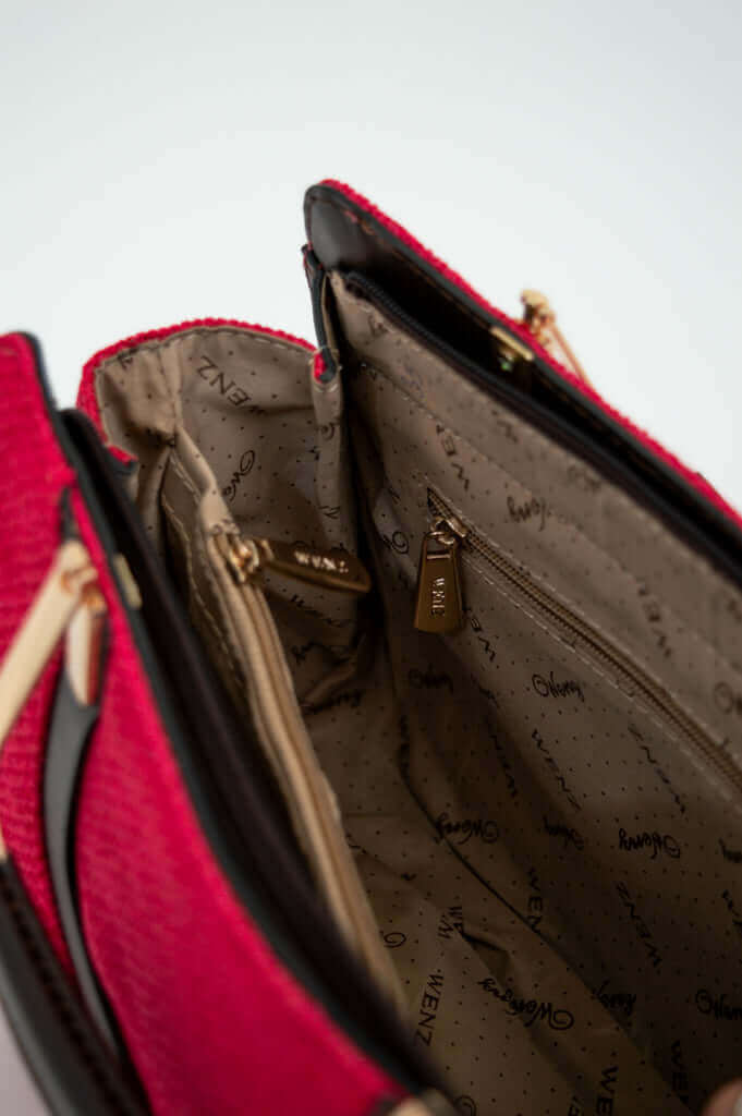 Detailed inside view of crimson satchel bag highlighting zippered pockets and WENZ lining