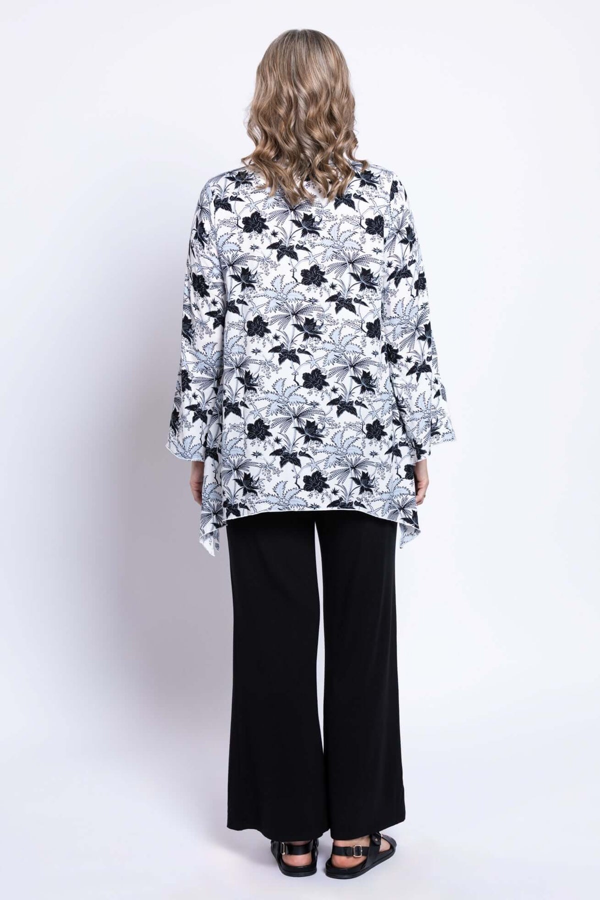 Back view of Dorothy black and white floral top showing flared sleeves and shark-bite hem