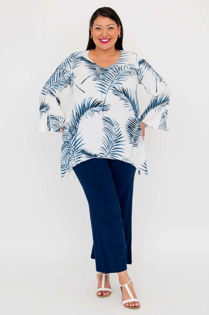 Woman in palm print top and navy pants, standing front pose with arms out