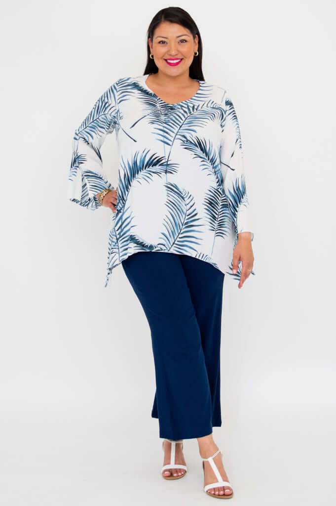 Model in Dorothy top with bell sleeves and navy pants standing on white background