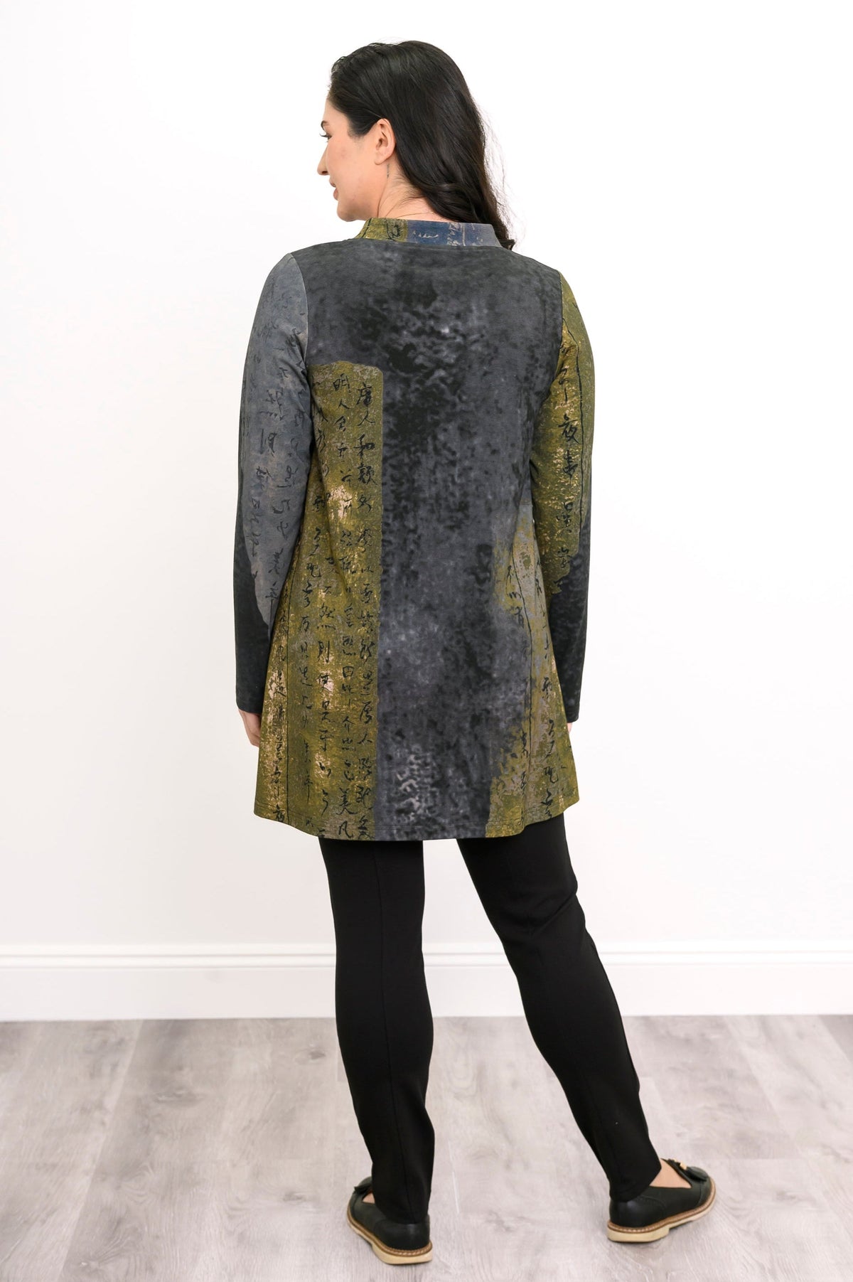 Rear view of an olive-grey print knit top, demonstrating the comfortable, hip-covering length on a model.