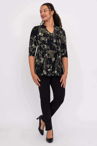 Woman looking sideways wearing the black and green abstract patterned top, black pants, and heels