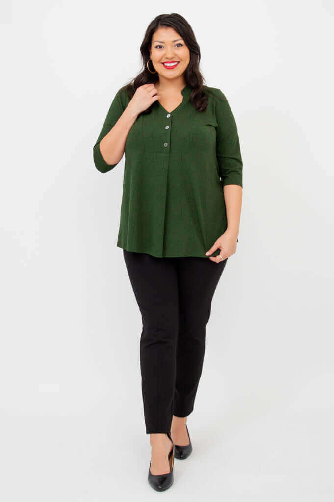 Woman in green bamboo V-neck top posing with hand to collar