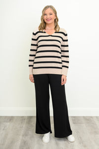 Model posing in a cream and black striped cotton sweater paired with relaxed black trousers, front view.
