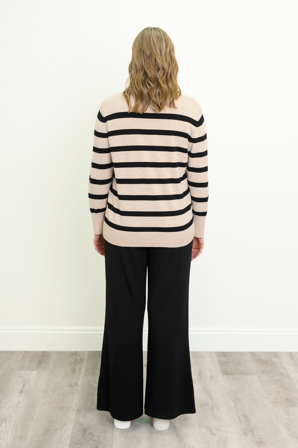 Back view of a beige and black striped cotton sweater, showcasing a clean back panel and straight, ribbed hem.