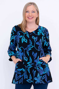 Woman wearing the Evelyn Top in blue floral pattern, showing V-neck and pockets