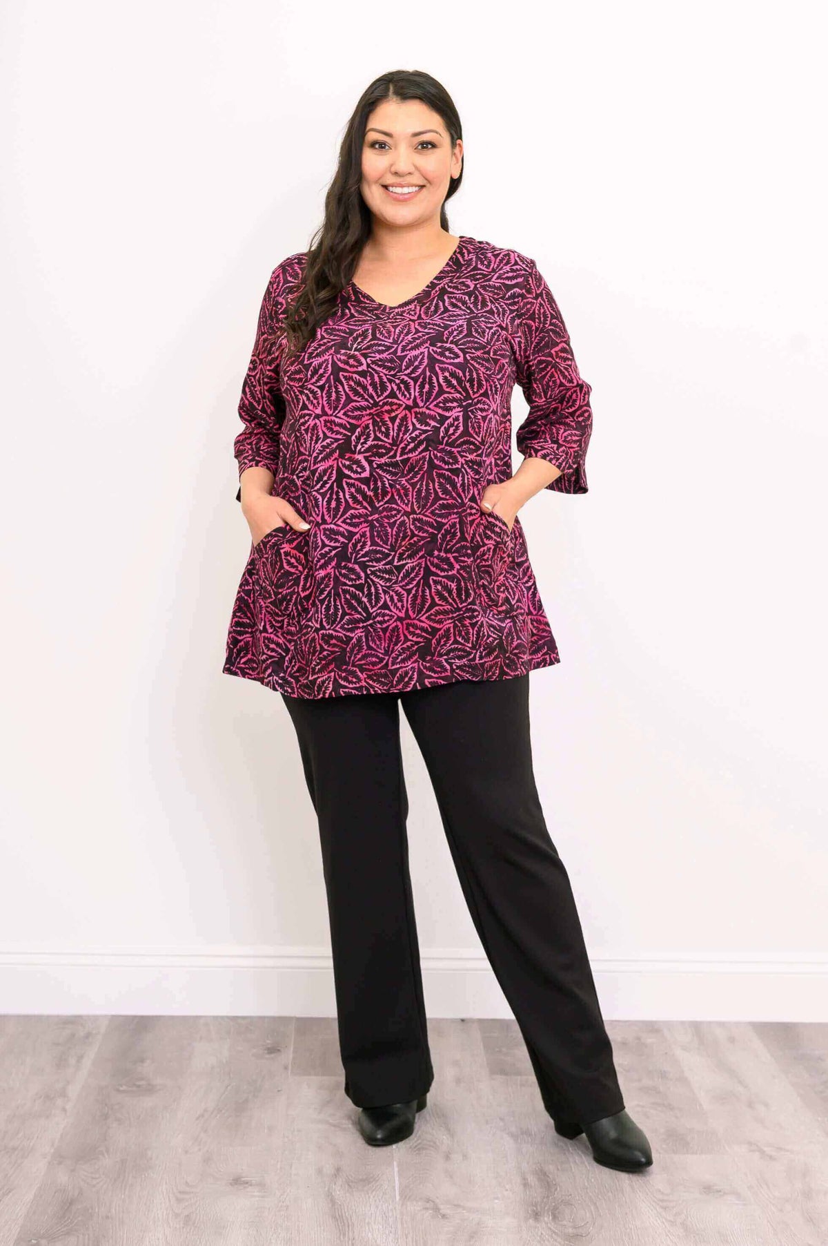 Woman standing with hands in patch pockets, wearing Evelyn Top in pink leaf print