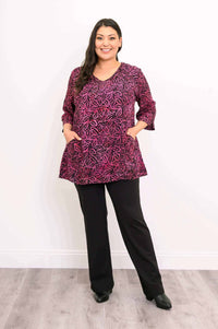 Woman standing with hands in patch pockets, wearing Evelyn Top in pink leaf print