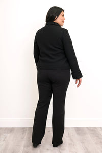 Full body back view of woman wearing a black collared jacket with folded sleeves