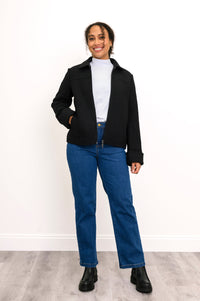Front view of woman with hand in pocket of her black carpenter style jacket