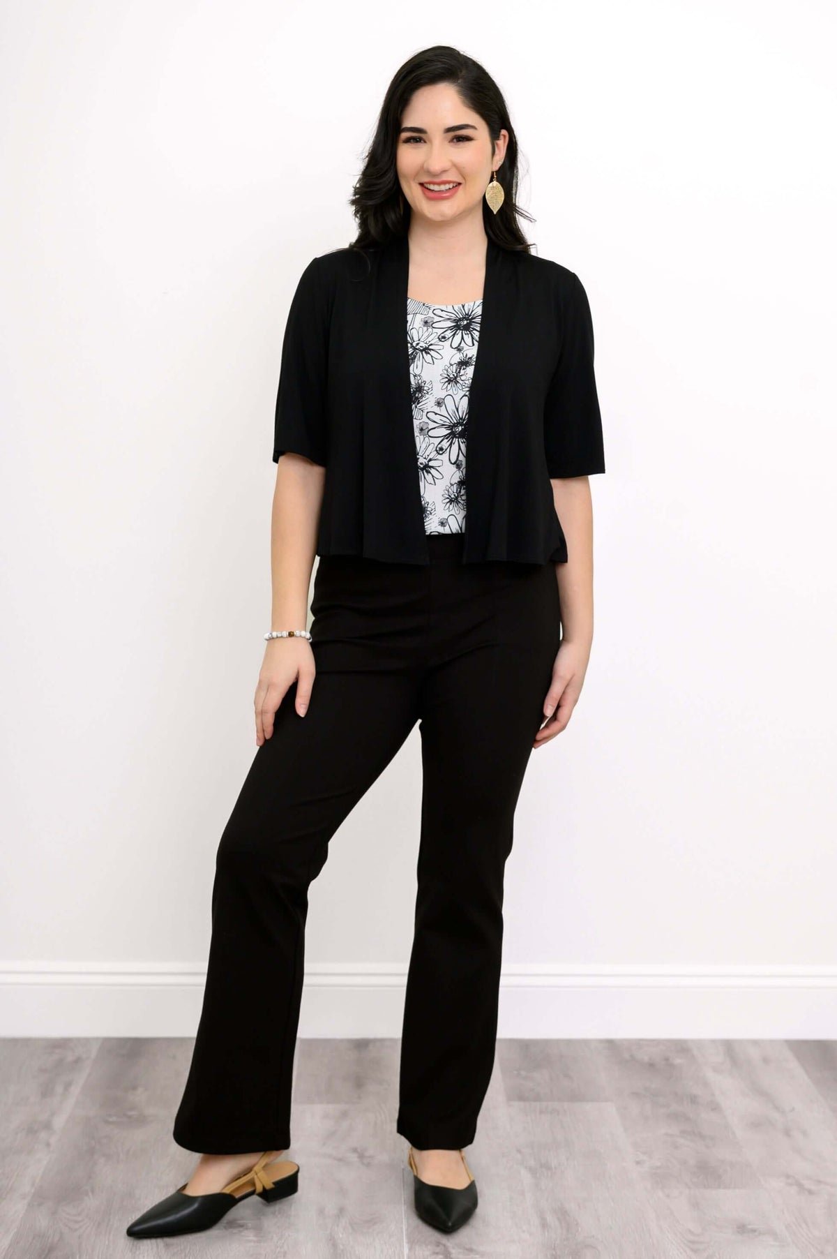 Woman wearing the black and white floral tank top styled with black pants and a black open cardigan