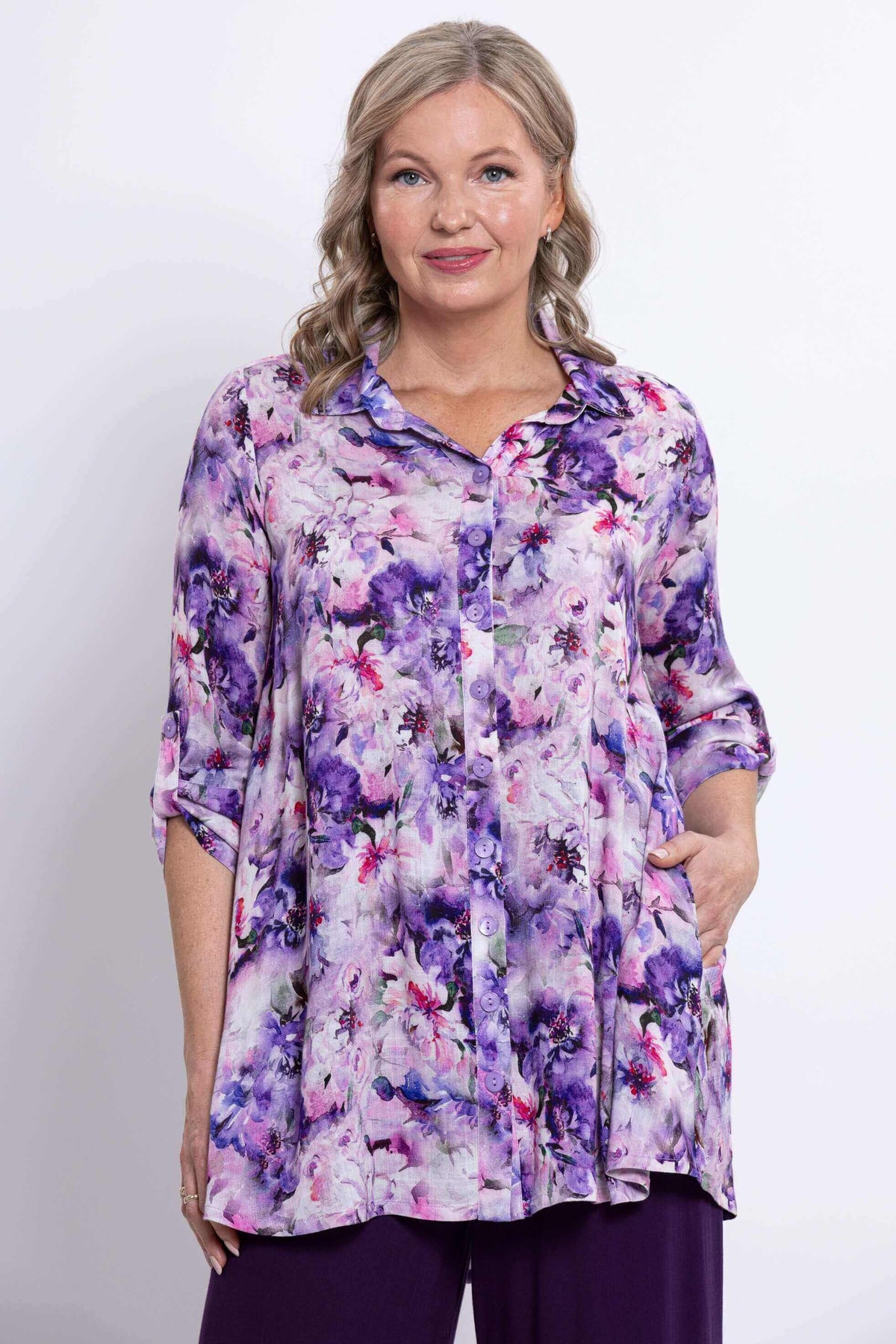 Woman wearing a purple and pink floral bamboo-linen tunic top with button front