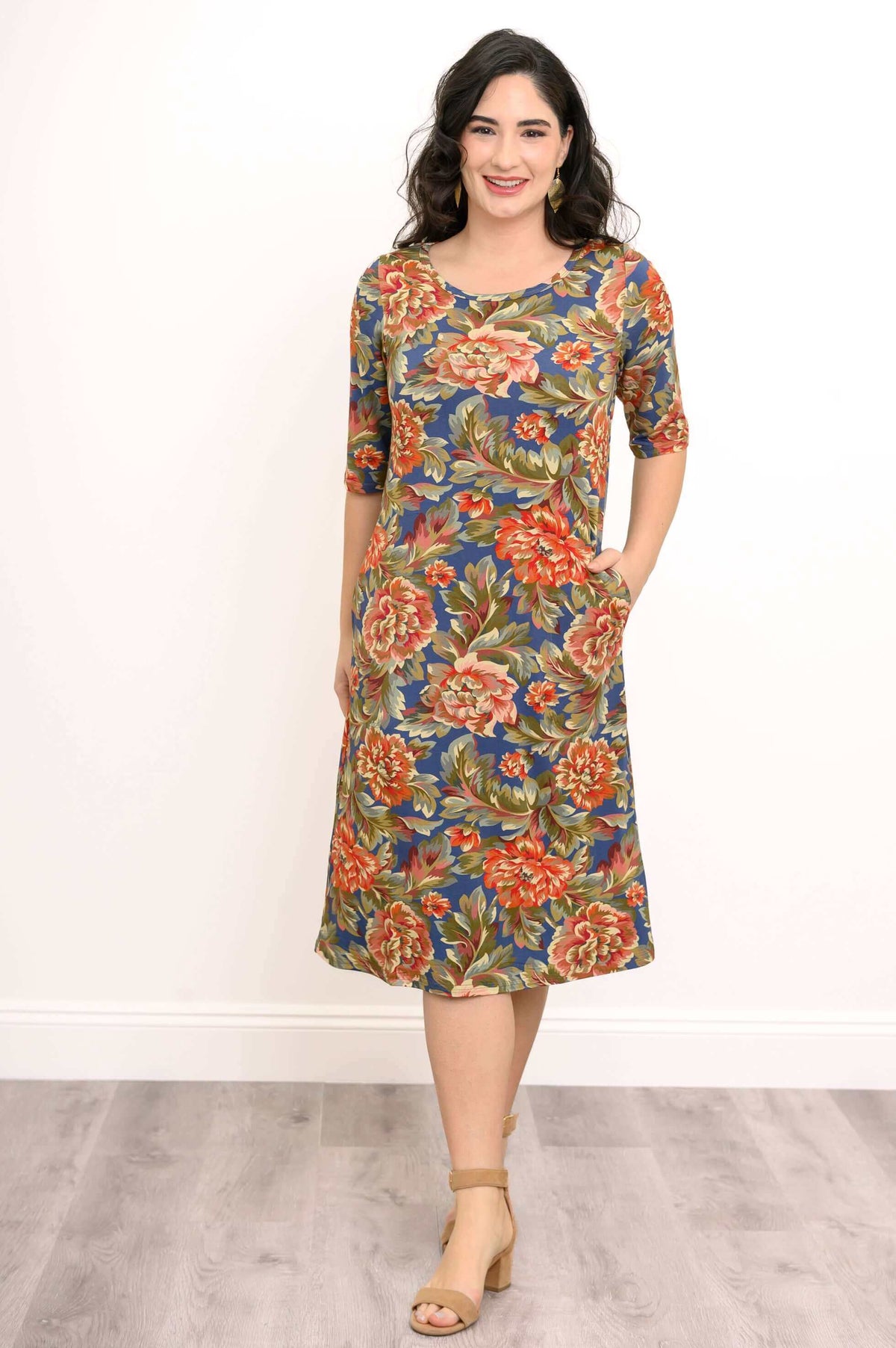 Woman wearing a knee-length floral bamboo dress with 3/4 sleeves, hands in pockets