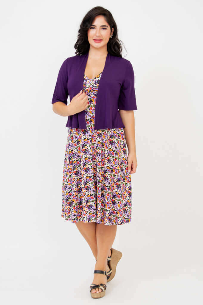 Woman modeling the floral dress paired with a purple short-sleeve cardigan
