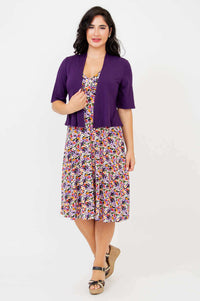 Woman modeling the floral dress paired with a purple short-sleeve cardigan
