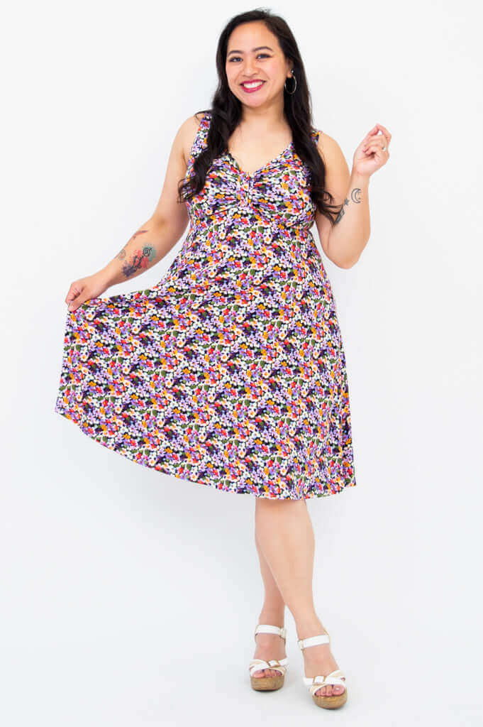Smiling woman holding out the skirt of a sleeveless floral dress