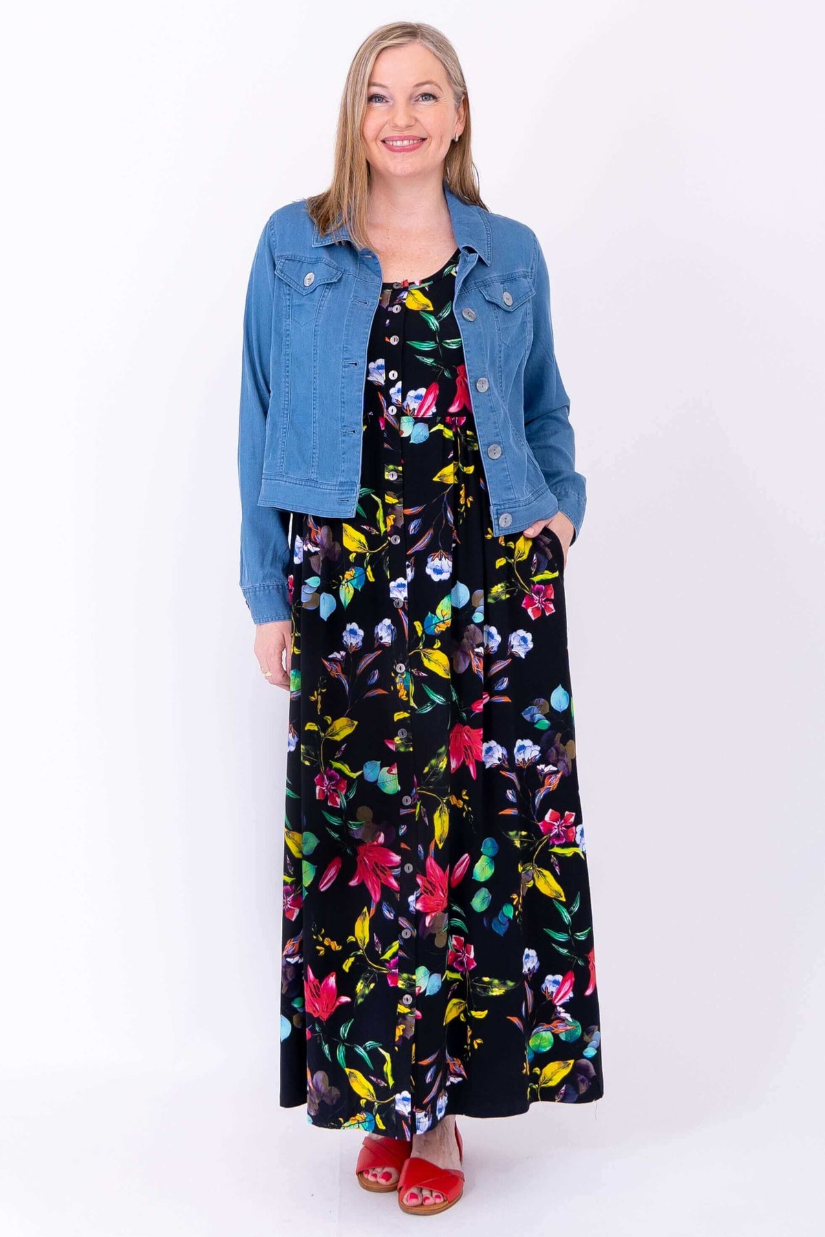 Floral maxi dress styled with a light blue denim jacket, modeled by smiling woman