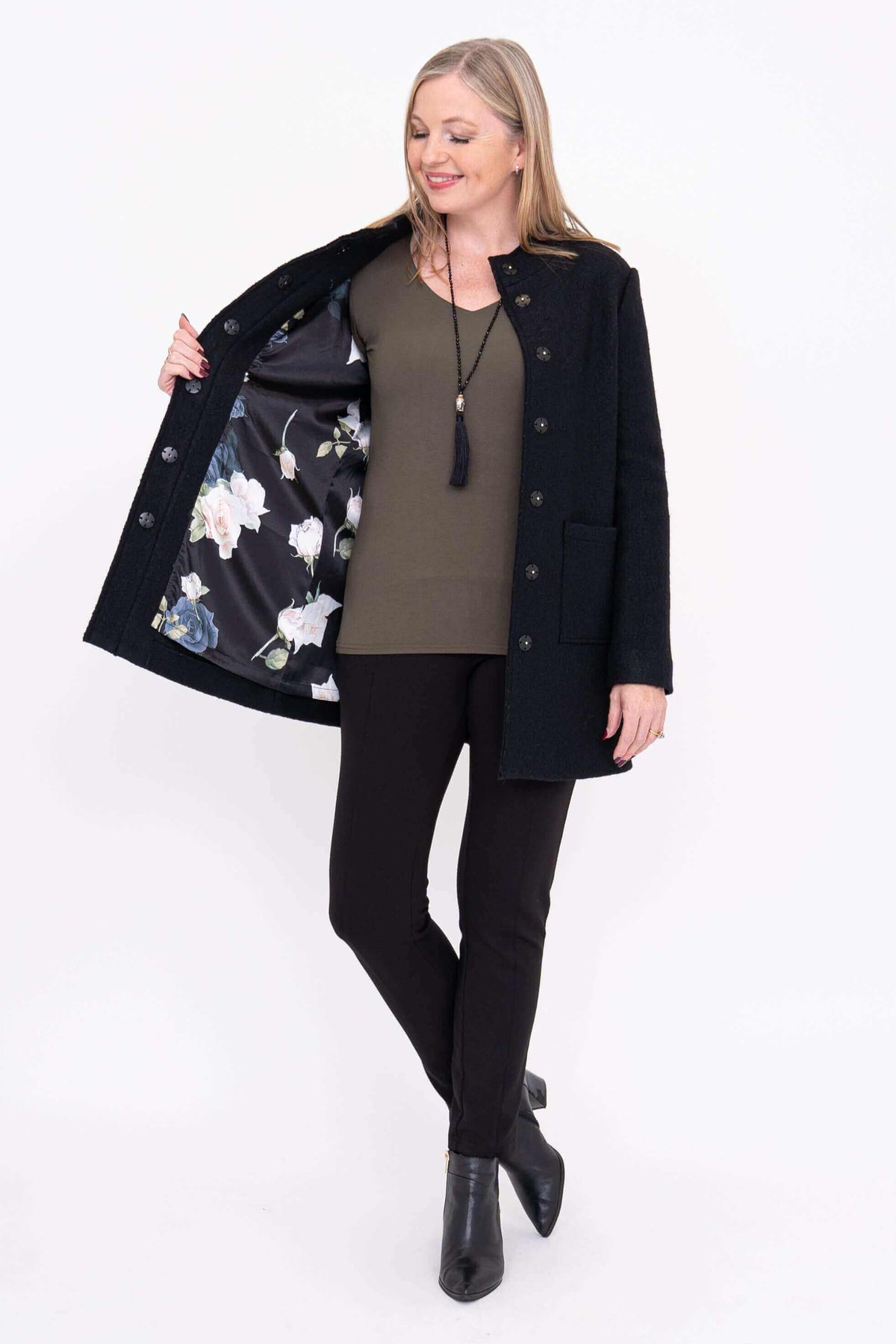 Woman opening black boiled wool coat to display floral satin lining