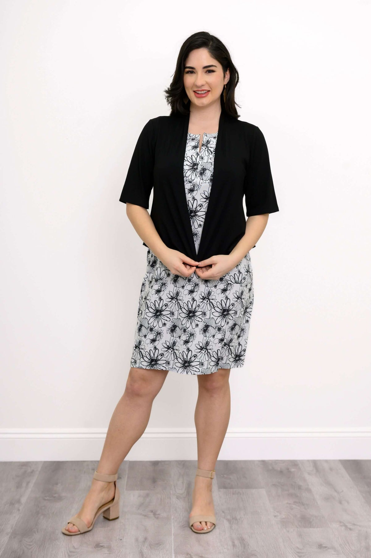 Woman in floral dress styled with a black open-front cardigan
