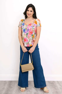 Woman in floral top and jeans holding a tan purse