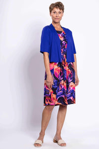 Woman wearing a vivid floral swirl dress paired with a royal blue short cardigan