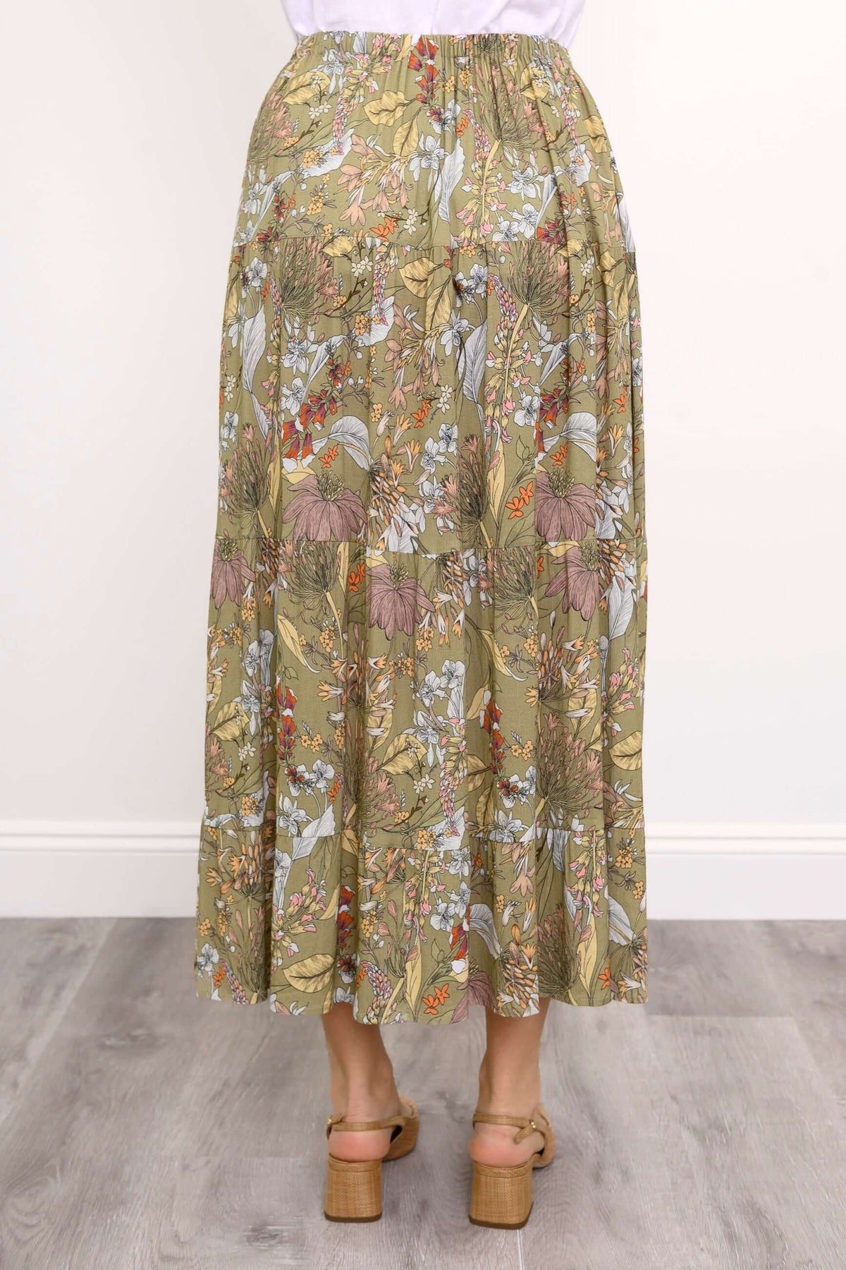 Back view of a floral tiered maxi skirt showing elastic waistband and soft pleats