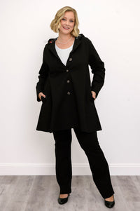 Front view of woman wearing black coat with buttons and black pants against a white background
