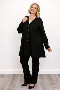 Front view of woman wearing black coat with buttons and black pants against a white background