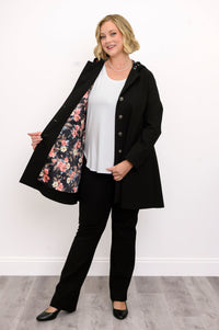 Front view of woman wearing black coat with floral lining and black pants against a white background