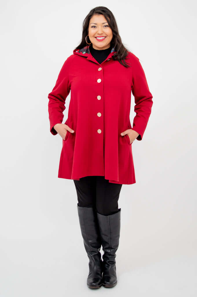 Person facing front in a buttoned berry red swing coat with hands in pockets