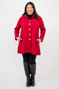 Person facing front in a buttoned berry red swing coat with hands in pockets