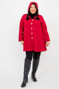 Person in berry red swing coat with hood up, standing and smiling