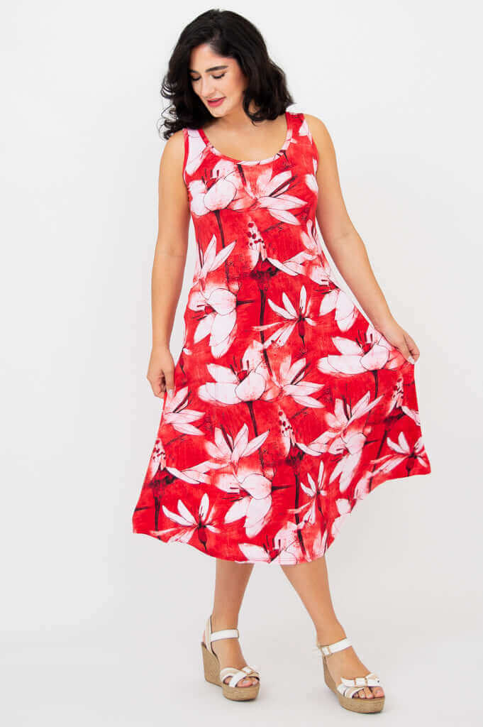 Woman gently holding the skirt of red floral tank dress, smiling