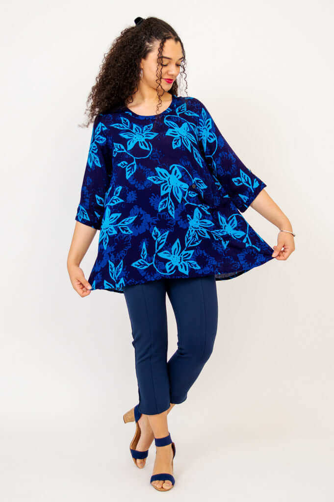 Woman holding out the hem of the Palace Blouse blue floral to show flowy fit