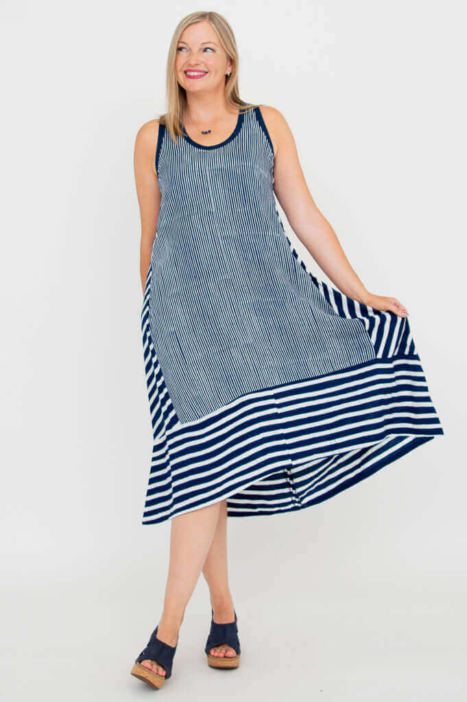 Woman modeling flowy navy and white striped hi-lo dress, showcasing side flair