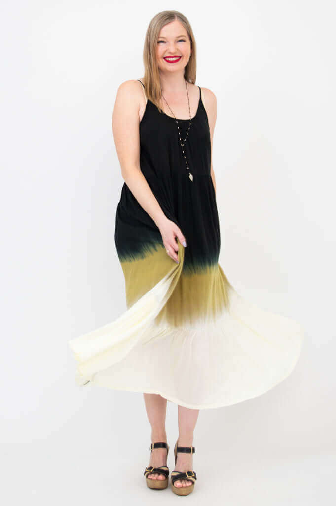 Woman twirling in a sleeveless black to golden ombre maxi dress showing its flowy fabric