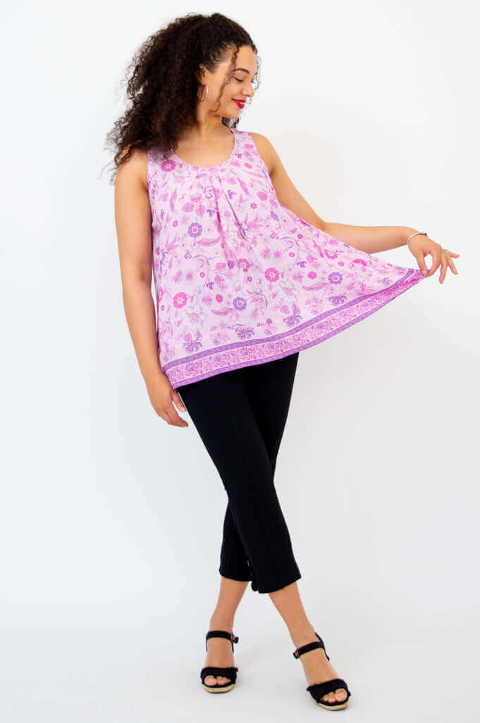 Model showing the flowy hem of a pink floral pleated tank top