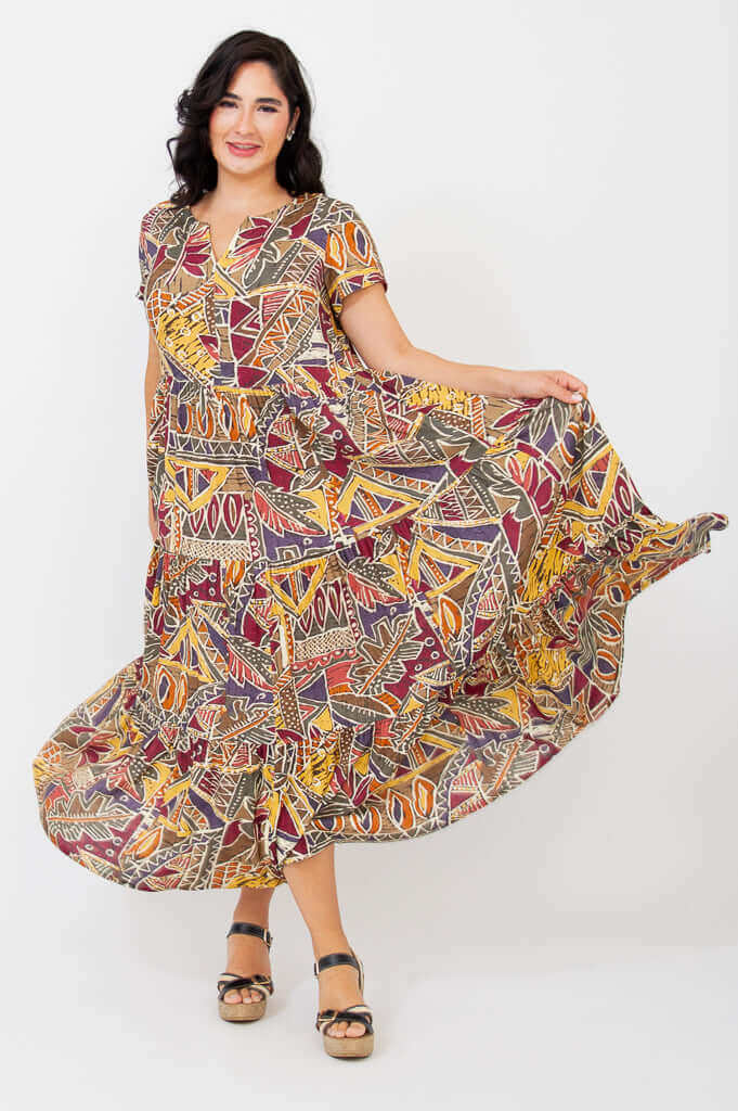 Woman swirling in a flowy geometric print maxi dress, side-front view