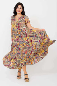Woman swirling in a flowy geometric print maxi dress, side-front view