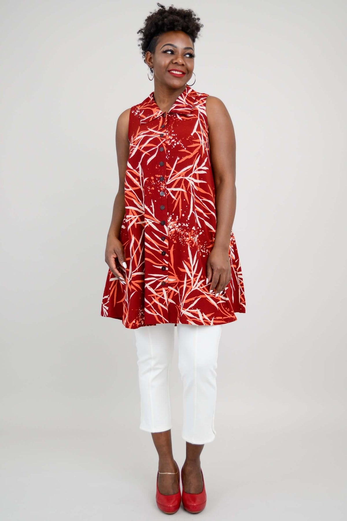 Woman facing forward wearing a ruby red bamboo print swing tank, smiling