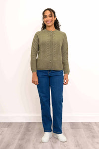 Front view of woman in green cable knit cashmere cardigan with pearl-like buttons and blue jeans