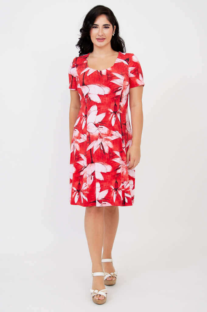 Woman standing in a front-facing pose wearing a red and white floral knee-length dress
