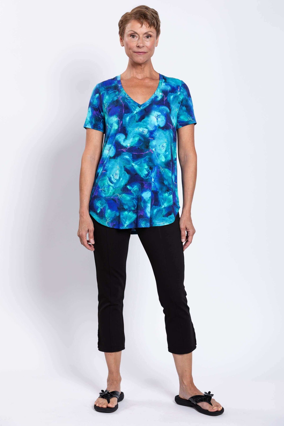 Front view of older woman in Jackie V-neck bamboo top in blue orchid with black capris