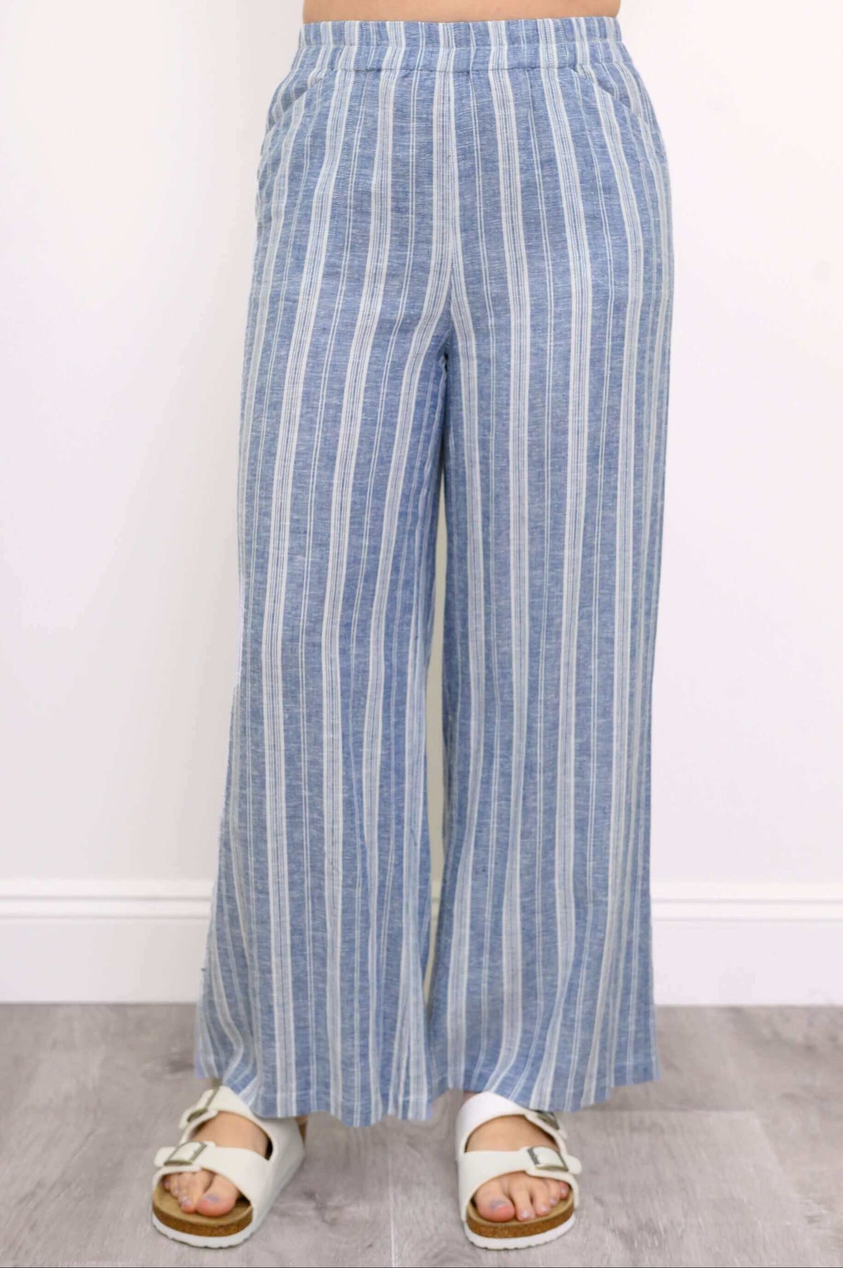 Front view of woman modeling a pair of blue and white striped pants with elastic waistband and wide-leg fit