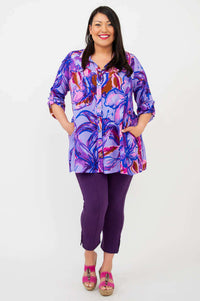 Front view of model in a loose-fitting purple floral tunic top with side pockets