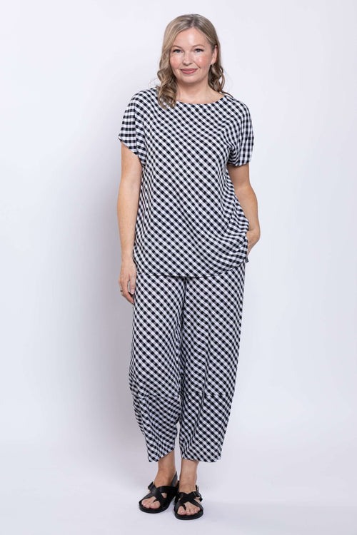 Model wearing black and white gingham barrel-leg cropped pants with matching top, front angle