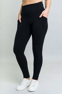 Front angled view of black fleece leggings with thigh pockets and wide waistband